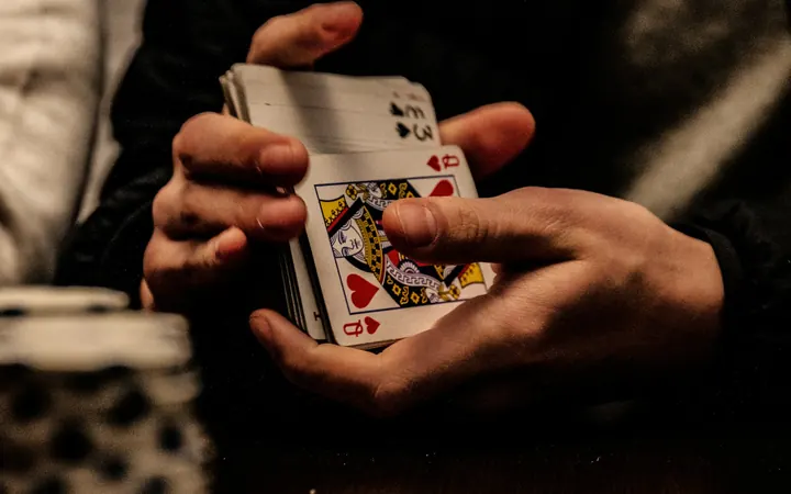 Dealer shuffling a deck of playing cards beside stacks of chips